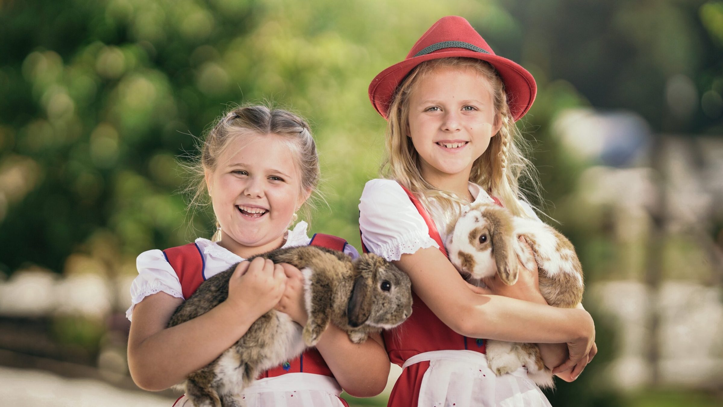 a little girl holding a teddy bear wearing a hat