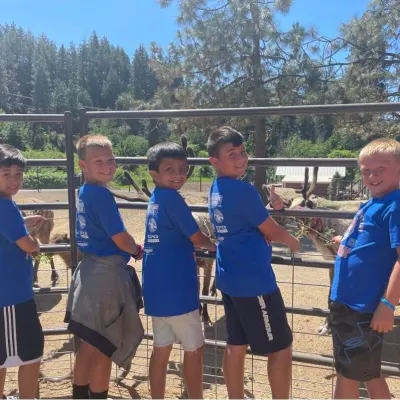 a group of young people standing next to a fence